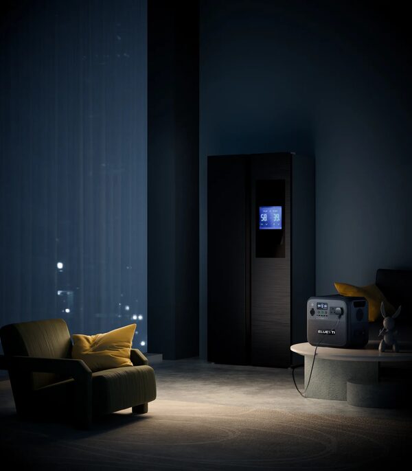 A BLUETTI portable power station on a table powering a fridge in a dark living room at night