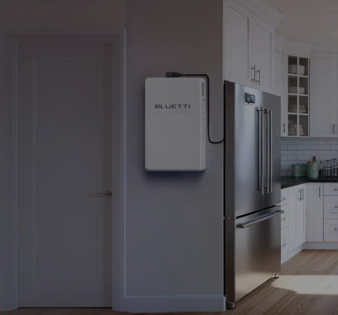 A white BLUETTI wall-mounted home battery installed on a kitchen wall next to a stainless steel fridge