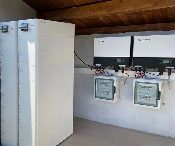 Growatt battery storage tower and two wall-mounted Growatt inverters with consumer units installed in a loft space