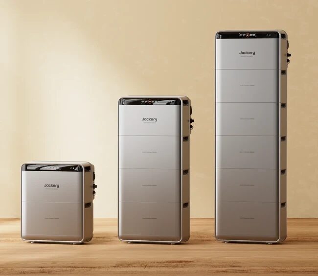 Three Jackery stackable home battery units of increasing size standing on a wooden floor