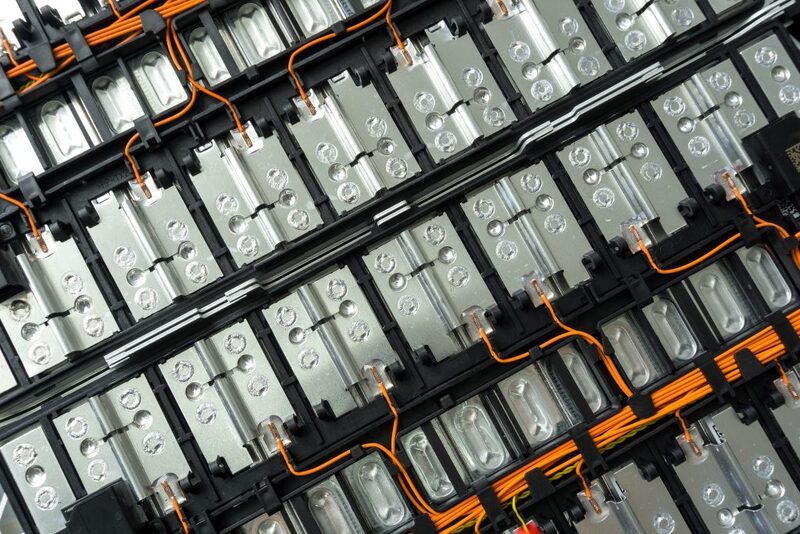 A close-up view of lithium-ion battery cells wired together with orange cabling inside a battery pack