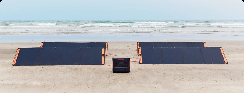 Two Jackery SolarSaga 200W portable folding solar panels on a beach connected to a Jackery portable power station