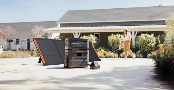 Jackery portable power stations with solar panels set up on a driveway outside a house