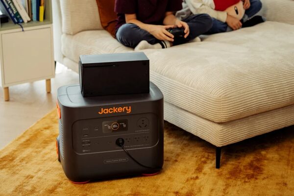 A Jackery portable power station powering a games console in a family living room