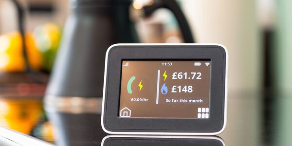 A smart meter in-home display on a kitchen counter showing electricity and gas costs so far this month