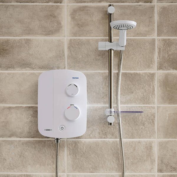 A white Triton AS2000SR electric power shower unit mounted on a tiled bathroom wall with a riser rail and shower head