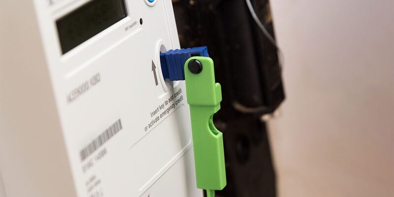 A prepayment electricity meter with a green key inserted into the card slot