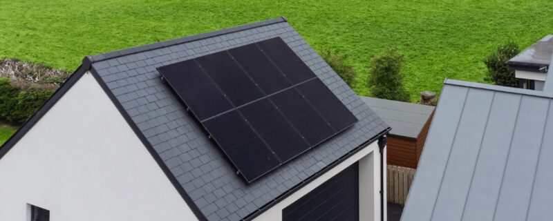 Aerial view of solar panels installed on the slate roof of a white house in the countryside