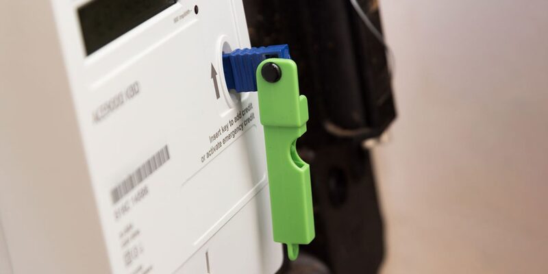 A close-up of a prepayment electricity meter with a green key inserted into the slot