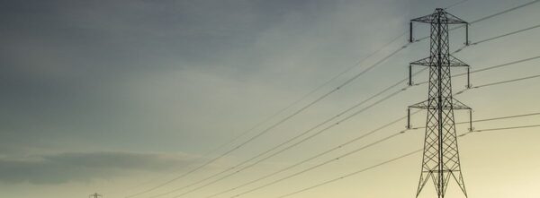 An electricity pylon with power lines against a dusky sky