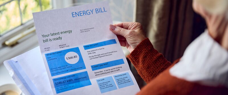 A person holding a printed energy bill showing a £366.85 balance and electricity usage