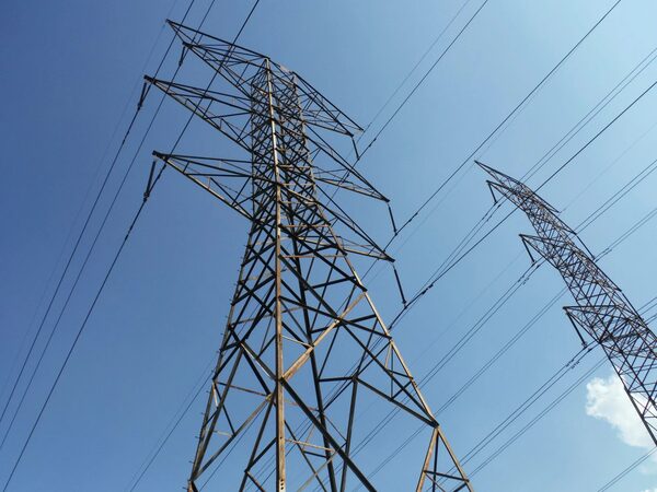 High-voltage electricity transmission pylons and power lines against a blue sky