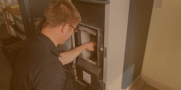 A technician servicing the interior of a biomass boiler in a utility room