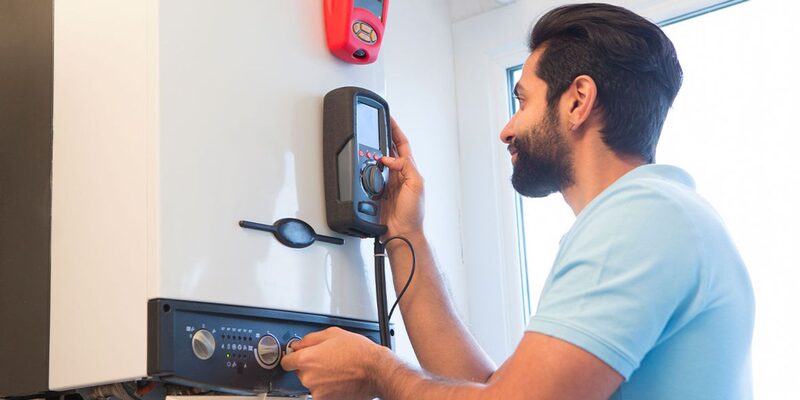 An engineer using a digital analyser to service a wall-mounted gas boiler