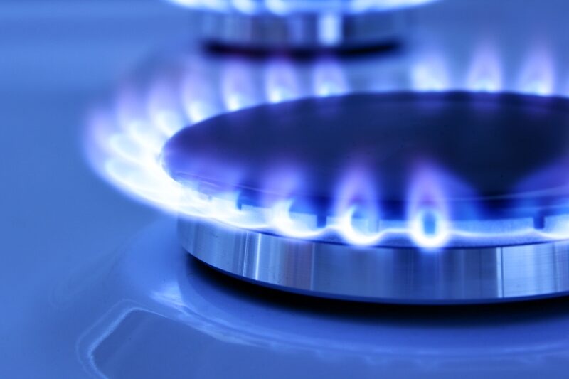 A close-up of a lit blue gas burner flame on a gas hob
