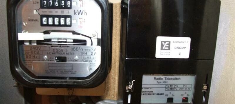 An Economy 7 electricity meter mounted next to a black Radio Teleswitch (Type A201) box on a wall