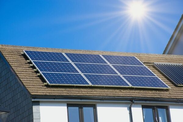 Solar panels installed on the tiled roof of a house under a bright sun