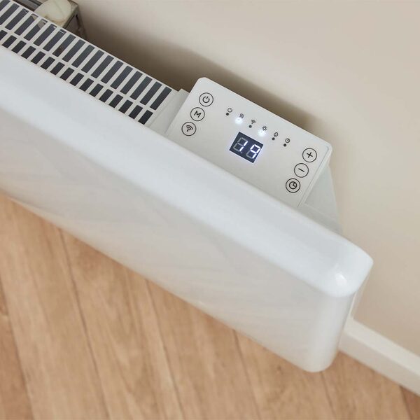 A white designer electric panel heater with a digital control panel mounted on a wall above a wooden floor