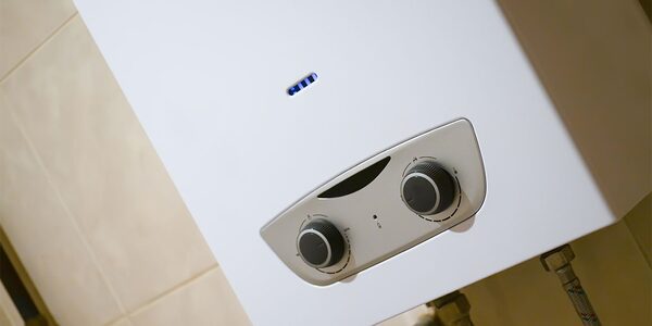 A white wall-mounted gas combi boiler with control dials installed against a tiled wall