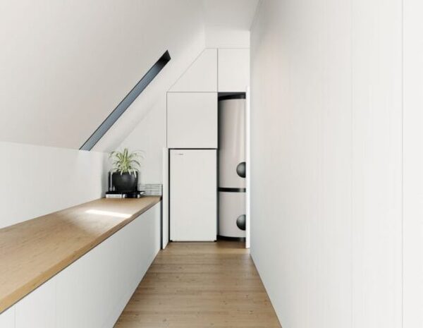 A hot water cylinder installed in a white cupboard in an attic room with a wooden worktop