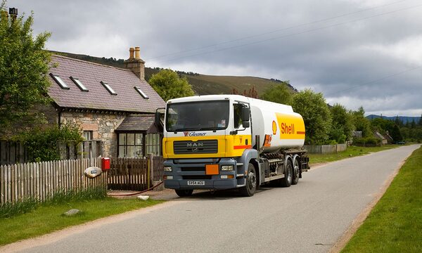 A Shell heating oil tanker lorry delivering fuel outside a stone cottage in the countryside