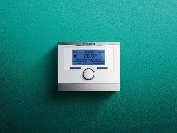 A Vaillant VRC 700 heating control thermostat mounted on a green wall