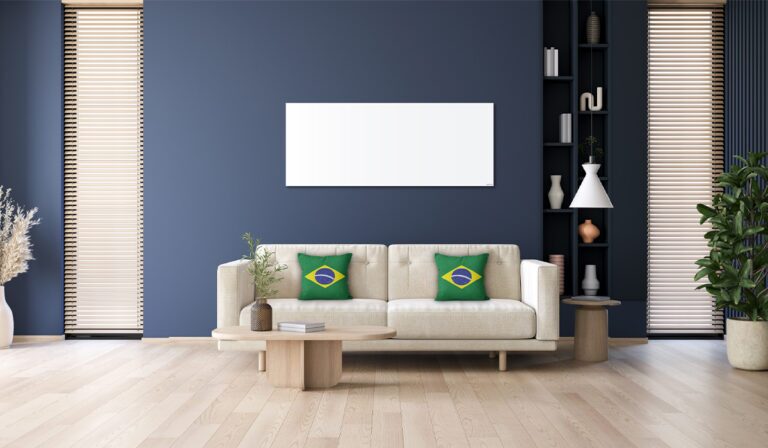 A white Herschel infrared heating panel mounted on a dark blue wall above a cream sofa with Brazilian flag cushions in a styled living room