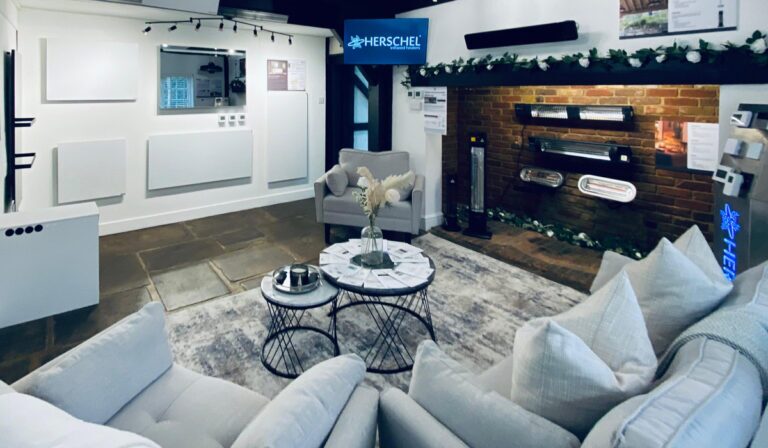 Herschel infrared heating showroom with various infrared heater panels and patio heaters displayed on walls and a brick fireplace