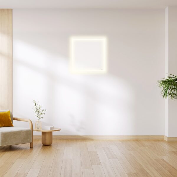 A white square Herschel infrared panel heater with a glowing front edge mounted high on a white wall in a bright minimalist living room
