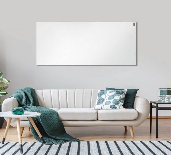 A white infrared heating panel mounted on a grey wall above a cream sofa in a living room