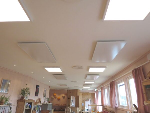 White infrared panel heaters mounted on the ceiling of a room alongside ceiling lights