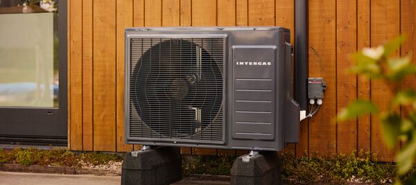 An Intergas air source heat pump unit installed outside a timber-clad house wall
