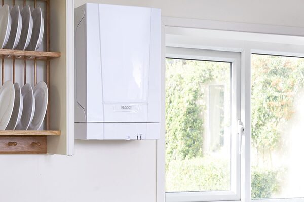 A white Baxi wall-mounted combi boiler installed in a bright kitchen next to a plate rack and window
