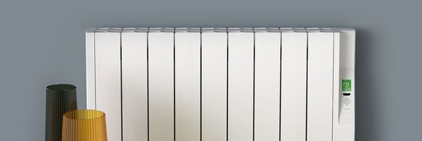 A white Rointe electric radiator mounted on a grey wall with a digital display and two decorative vases beside it