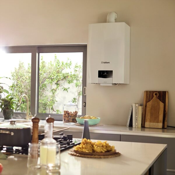 A white Vaillant ecoTEC plus wall-mounted combi boiler installed on a cream kitchen wall above a worktop