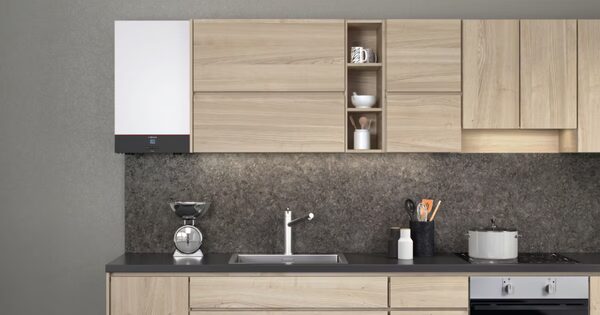 A white Viessmann Vitodens combi boiler mounted on a grey wall above a modern kitchen worktop with sink, scales and utensils
