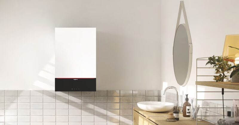 A white Viessmann wall-mounted gas combi boiler installed on a tiled bathroom wall above a wooden vanity with a basin and mirror