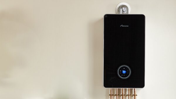 A black wall-mounted Worcester combi boiler with copper pipes below, installed on a plain wall