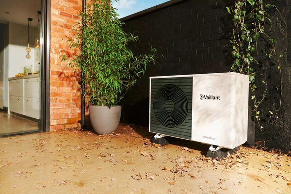 A Vaillant air source heat pump installed outside a house next to a potted plant