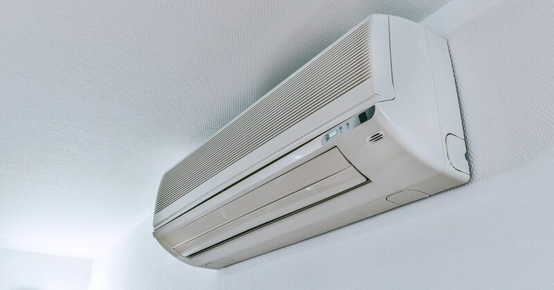 A white wall-mounted split air conditioning indoor unit installed high on a white wall