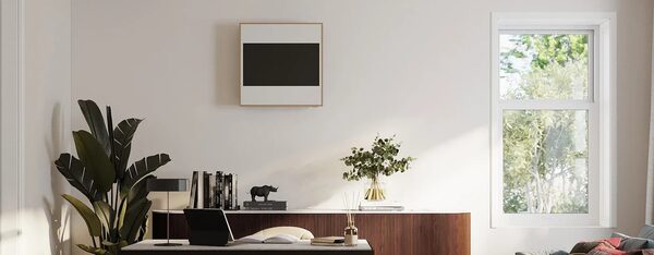 A wall-mounted LG Artcool air conditioning unit styled like a framed picture above a sideboard in a bright living room