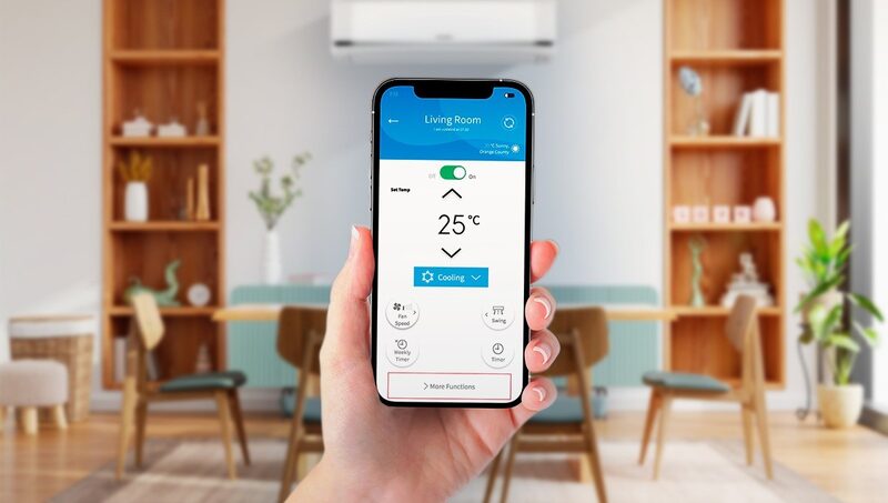 A hand holding a smartphone showing an air conditioning control app in front of a wall-mounted Hitachi air conditioning unit in a dining room