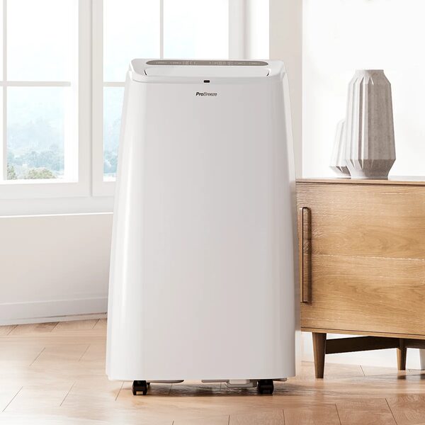 A white Pro Breeze portable air conditioner standing on wooden flooring in a bright room next to a sideboard