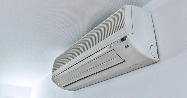 A white wall-mounted split air conditioning indoor unit installed high on a white wall