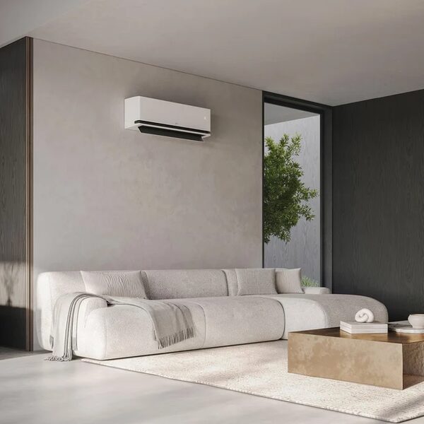 A white wall-mounted air conditioning unit installed above a sofa in a modern minimalist living room