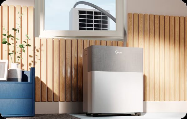A Midea portable air conditioner standing in a wood-panelled room with its exhaust hose vented through a window