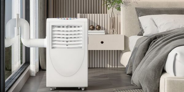 A white portable air conditioner with an exhaust hose out the window, standing in a modern bedroom