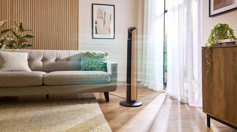 A Dimplex tower fan standing in a bright living room next to a grey sofa