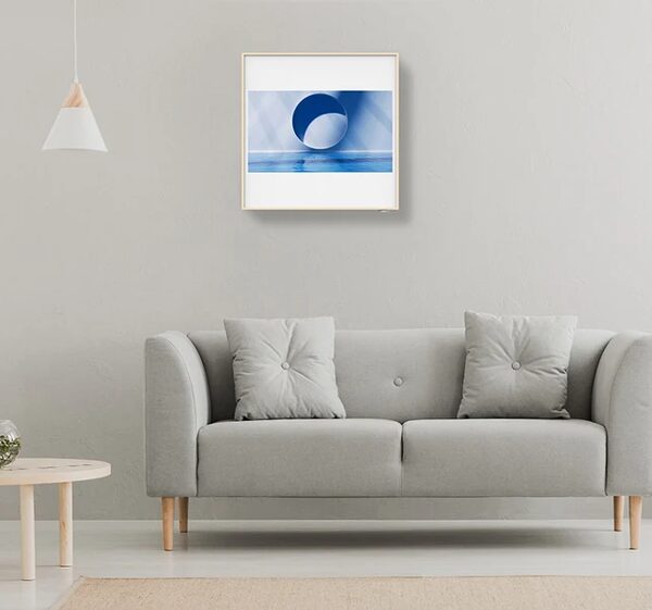 A wall-mounted LG Artcool air conditioning unit styled as a framed picture above a grey sofa in a living room