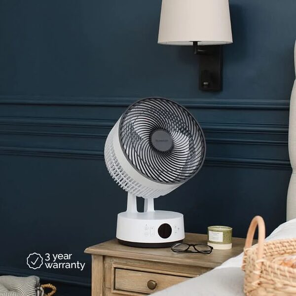 A white MeacoFan Sefte Pro table air circulator fan sitting on a wooden bedside table in a bedroom